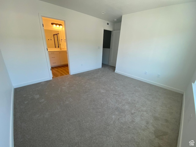 unfurnished bedroom with carpet flooring, baseboards, and connected bathroom