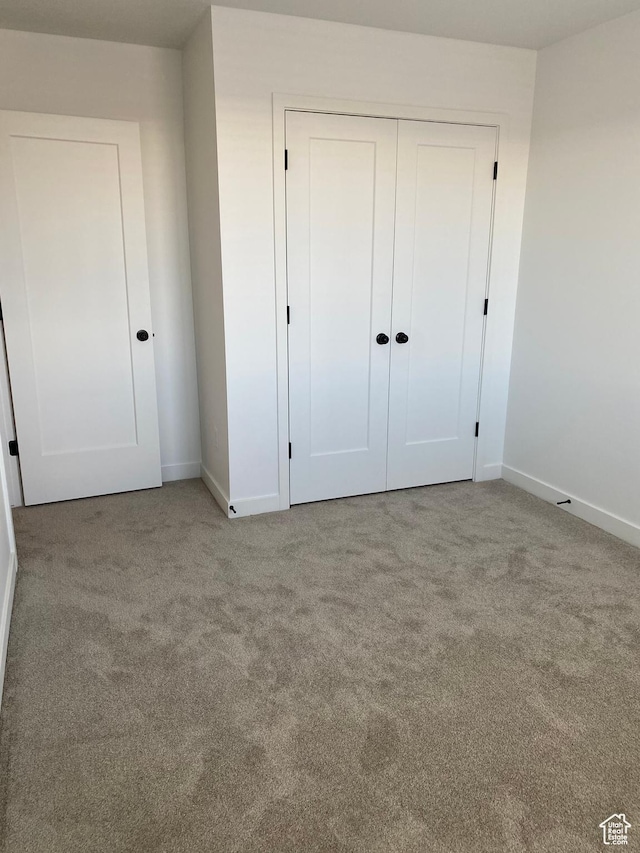 unfurnished bedroom featuring baseboards, carpet, and a closet