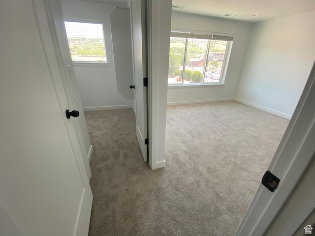 unfurnished room featuring light carpet, baseboards, and a healthy amount of sunlight