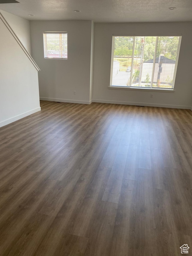 unfurnished living room with baseboards and dark wood-style flooring