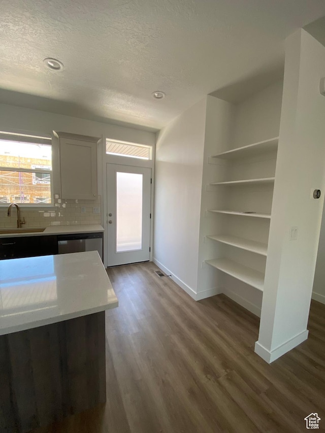kitchen featuring a textured ceiling, baseboards, a sink, and dark wood-type flooring