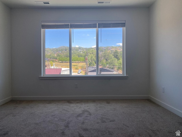 carpeted empty room featuring visible vents and baseboards