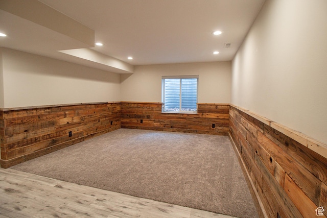 basement featuring recessed lighting, a wainscoted wall, wooden walls, visible vents, and carpet flooring