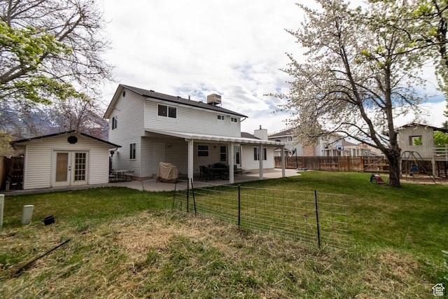 back of property featuring french doors, a fenced backyard, an outbuilding, a yard, and a patio