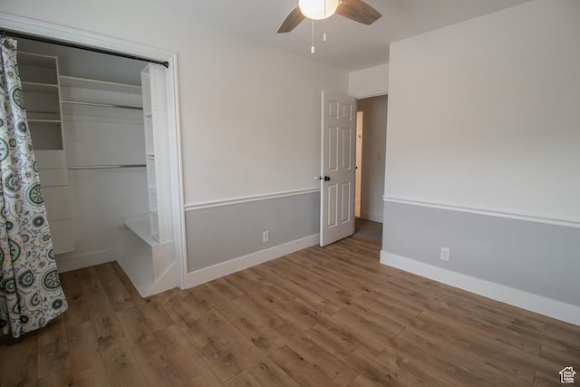 unfurnished bedroom featuring baseboards, a ceiling fan, wood finished floors, and a closet