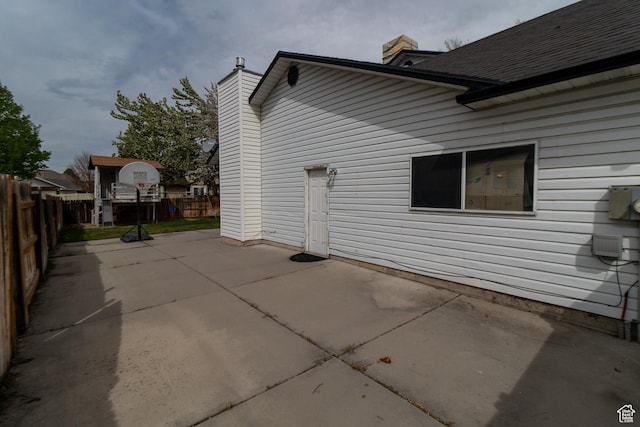view of property exterior with a patio, a chimney, and fence