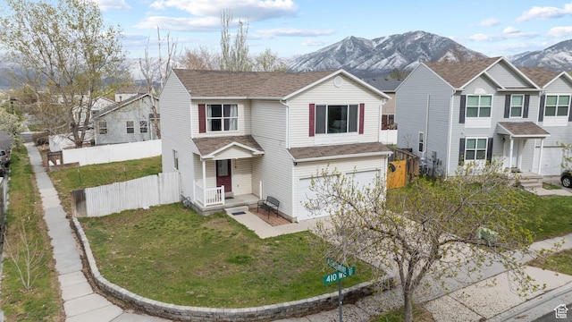 718 N 410 W, Tooele, UT 84074 - traditional home featuring a front lawn, a shingled roof, fence, a mountain view, and a garage