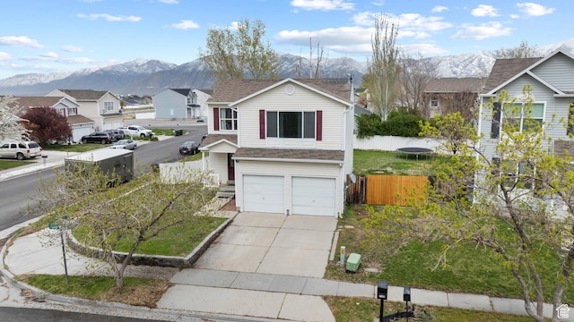 traditional-style home featuring an attached garage, driveway, fence, and a mountain view