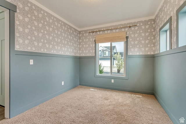 spare room with wainscoting, carpet floors, crown molding, and wallpapered walls