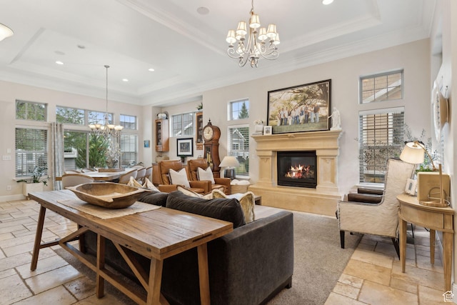 living room with a raised ceiling, stone tile floors, a glass covered fireplace, and an inviting chandelier