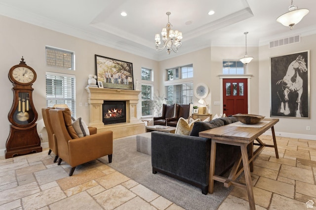 living area with stone tile floors, a glass covered fireplace, visible vents, and a raised ceiling
