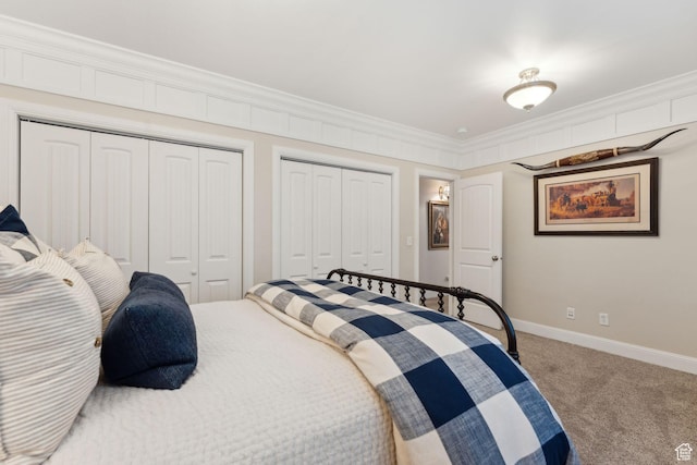 bedroom featuring multiple closets, baseboards, carpet floors, and crown molding
