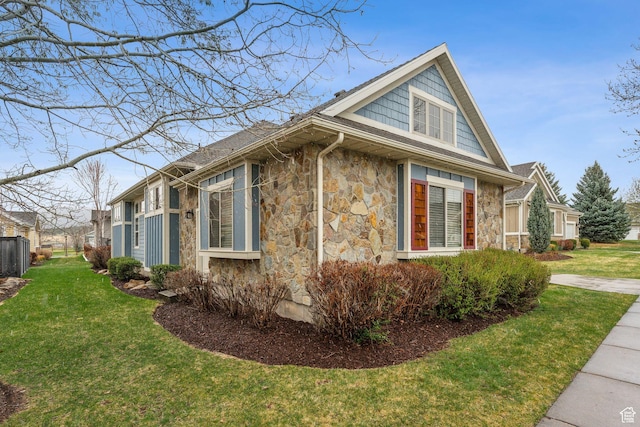 view of side of home with a lawn, fence, and stone siding