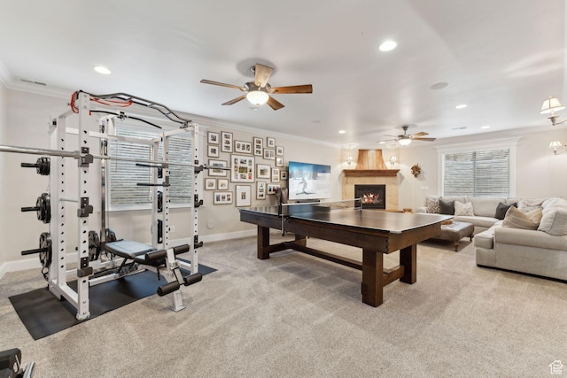 rec room featuring recessed lighting, ornamental molding, baseboards, a lit fireplace, and ceiling fan