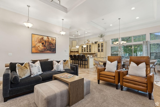 living area featuring a notable chandelier, ornamental molding, and a raised ceiling
