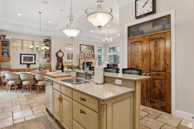 kitchen with stone tile floors, a chandelier, cream cabinetry, and a raised ceiling