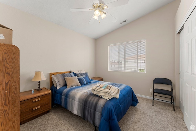 bedroom featuring lofted ceiling, visible vents, a ceiling fan, light carpet, and a closet