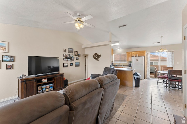 living room featuring lofted ceiling, visible vents, light tile patterned floors, baseboards, and ceiling fan