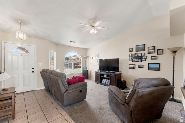 living area with a ceiling fan, a textured ceiling, light tile patterned floors, lofted ceiling, and visible vents