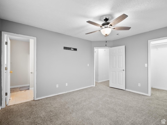 unfurnished bedroom with a walk in closet, carpet, baseboards, and connected bathroom