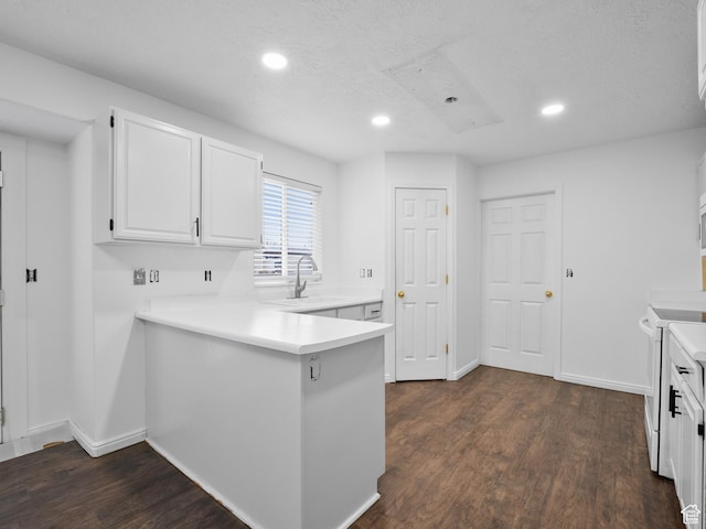 kitchen with recessed lighting, white cabinets, a sink, a peninsula, and dark wood-style flooring