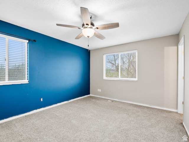 carpeted empty room with baseboards, a textured ceiling, and ceiling fan