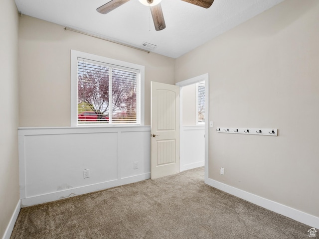 unfurnished room with visible vents, carpet floors, ceiling fan, and a healthy amount of sunlight