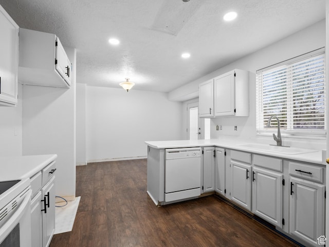 kitchen featuring a peninsula, a sink, dark wood finished floors, recessed lighting, and white appliances