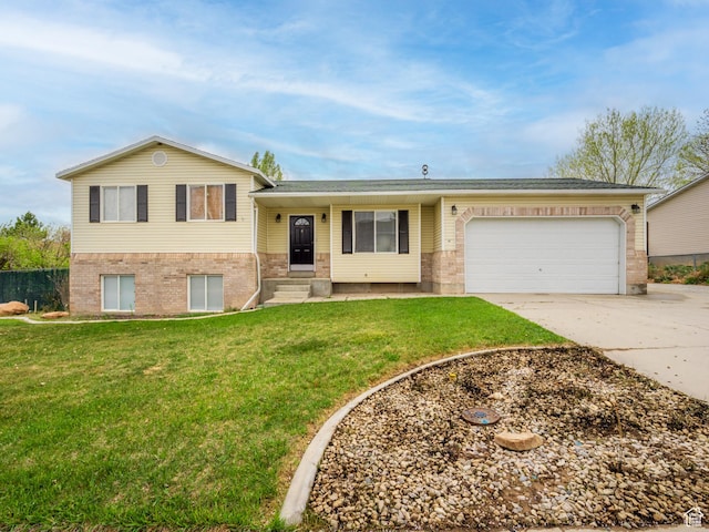 tri-level home featuring an attached garage, brick siding, a front yard, and concrete driveway