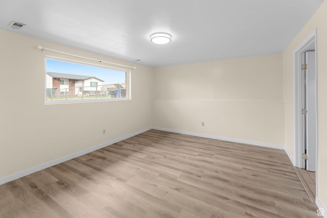 unfurnished room with light wood-type flooring, visible vents, and baseboards