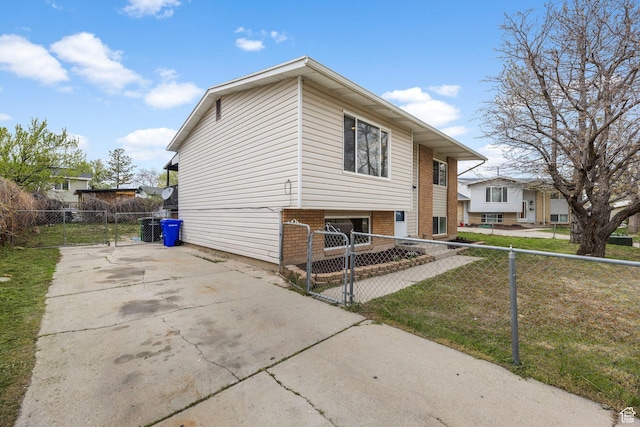 view of side of property with a gate, fence private yard, driveway, and brick siding