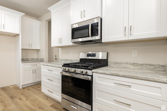 2187 W 320 S, Hurricane, UT 84737 - kitchen featuring stainless steel appliances, light stone counters, light wood-style floors, and white cabinetry