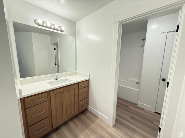 1975 S Marigold Way Unit 433, Santaquin, UT 84655 - bathroom with wood finished floors, vanity, washtub / shower combination, a textured ceiling, and baseboards