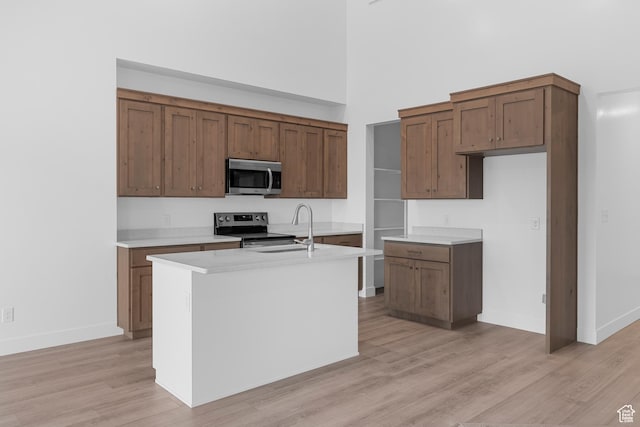 1975 S Marigold Way Unit 433, Santaquin, UT 84655 - kitchen with appliances with stainless steel finishes, light wood finished floors, light countertops, an island with sink, and a towering ceiling