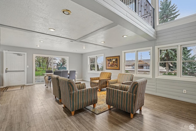 living area with baseboards, wood finished floors, a textured ceiling, and recessed lighting