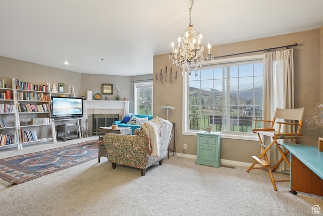 living area with carpet, a tiled fireplace, baseboards, and an inviting chandelier