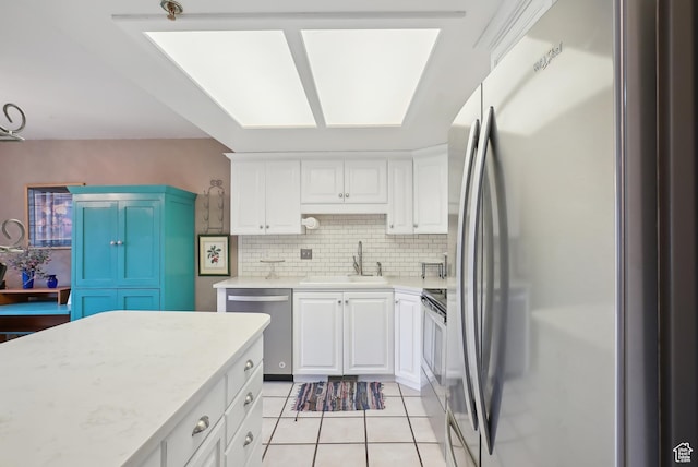 kitchen with a sink, light tile patterned floors, light countertops, backsplash, and appliances with stainless steel finishes