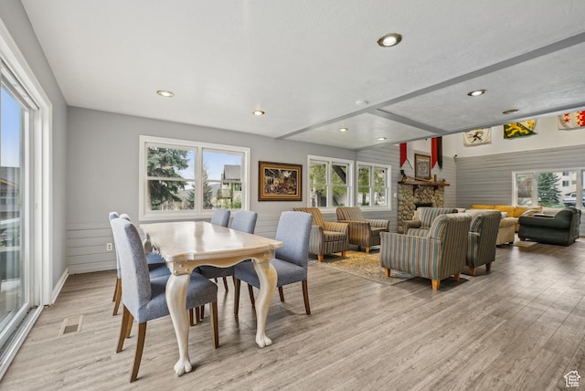 dining area with recessed lighting, light wood finished floors, a stone fireplace, visible vents, and beamed ceiling