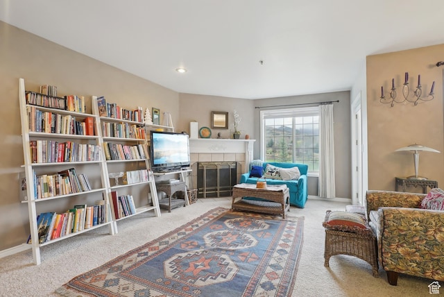 sitting room with a tiled fireplace, baseboards, and carpet