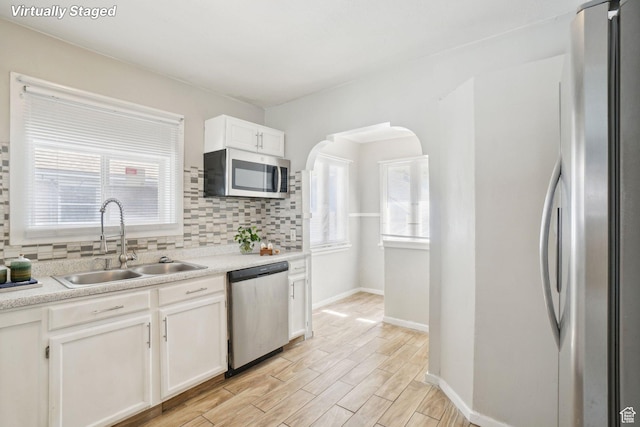 2662 Jackson Ave, Ogden, UT 84401 - kitchen featuring tasteful backsplash, a sink, white cabinetry, baseboards, and appliances with stainless steel finishes