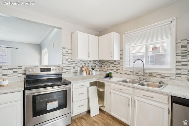 2662 Jackson Ave, Ogden, UT 84401 - kitchen featuring white cabinets, light wood finished floors, a sink, tasteful backsplash, and appliances with stainless steel finishes