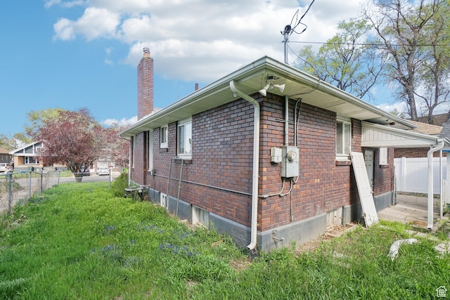2662 Jackson Ave, Ogden, UT 84401 - view of property exterior with brick siding, a yard, a chimney, and fence