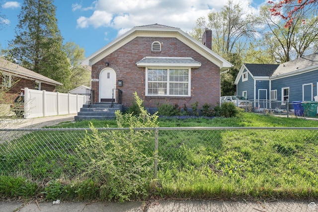 bungalow featuring brick siding, entry steps, a fenced backyard, and a chimney