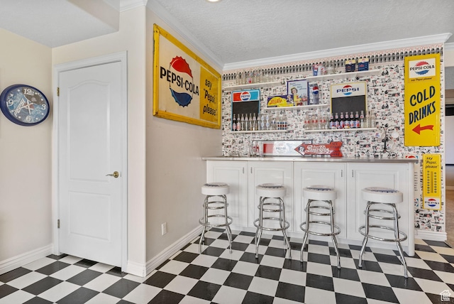 bar featuring baseboards, crown molding, a dry bar, and tile patterned floors