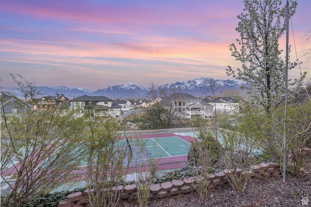 view of tennis court with a mountain view, fence, and a residential view