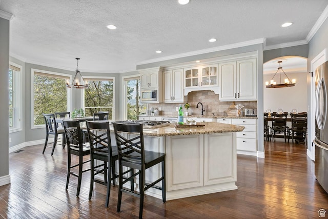 kitchen featuring a chandelier, dark wood finished floors, light stone counters, and stainless steel appliances