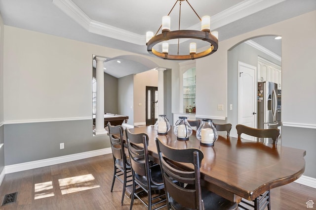 dining space with ornamental molding, wood finished floors, arched walkways, and ornate columns