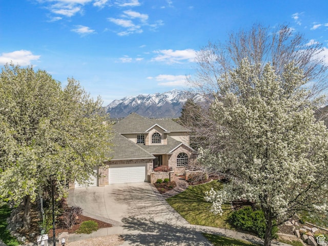 view of front of property featuring a mountain view, driveway, brick siding, a garage, and a shingled roof