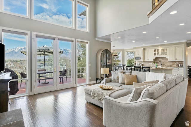 living room featuring recessed lighting, a high ceiling, dark wood-type flooring, and ornamental molding