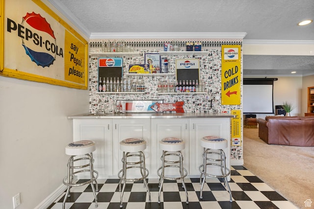 bar featuring tile patterned floors, a textured ceiling, baseboards, wet bar, and ornamental molding